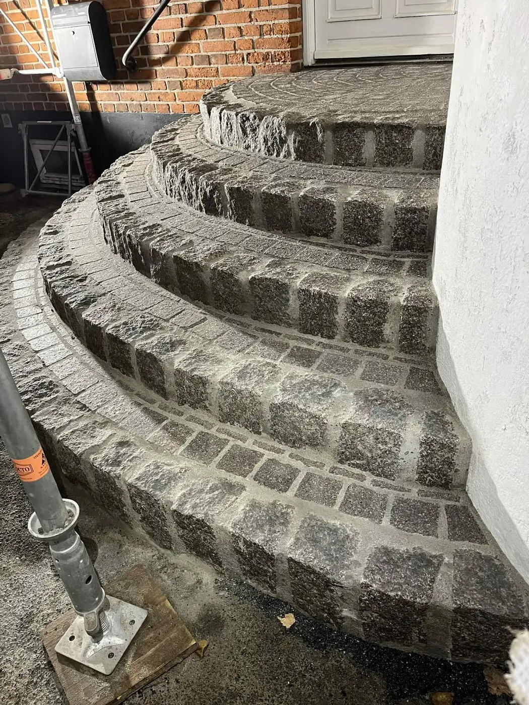 Buet udendoers trappe muret i graa chaussesten foran hvid husmur