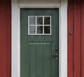 Grøn hoveddør med hvid karm og små ruder i rød træfacade