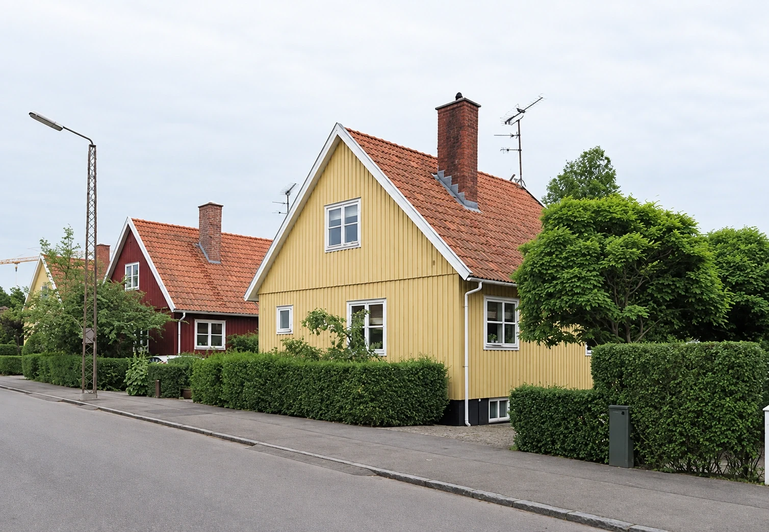 Gult svenskerhus med rødt tegltag, hvide vinduer og muret skorsten i Rønne