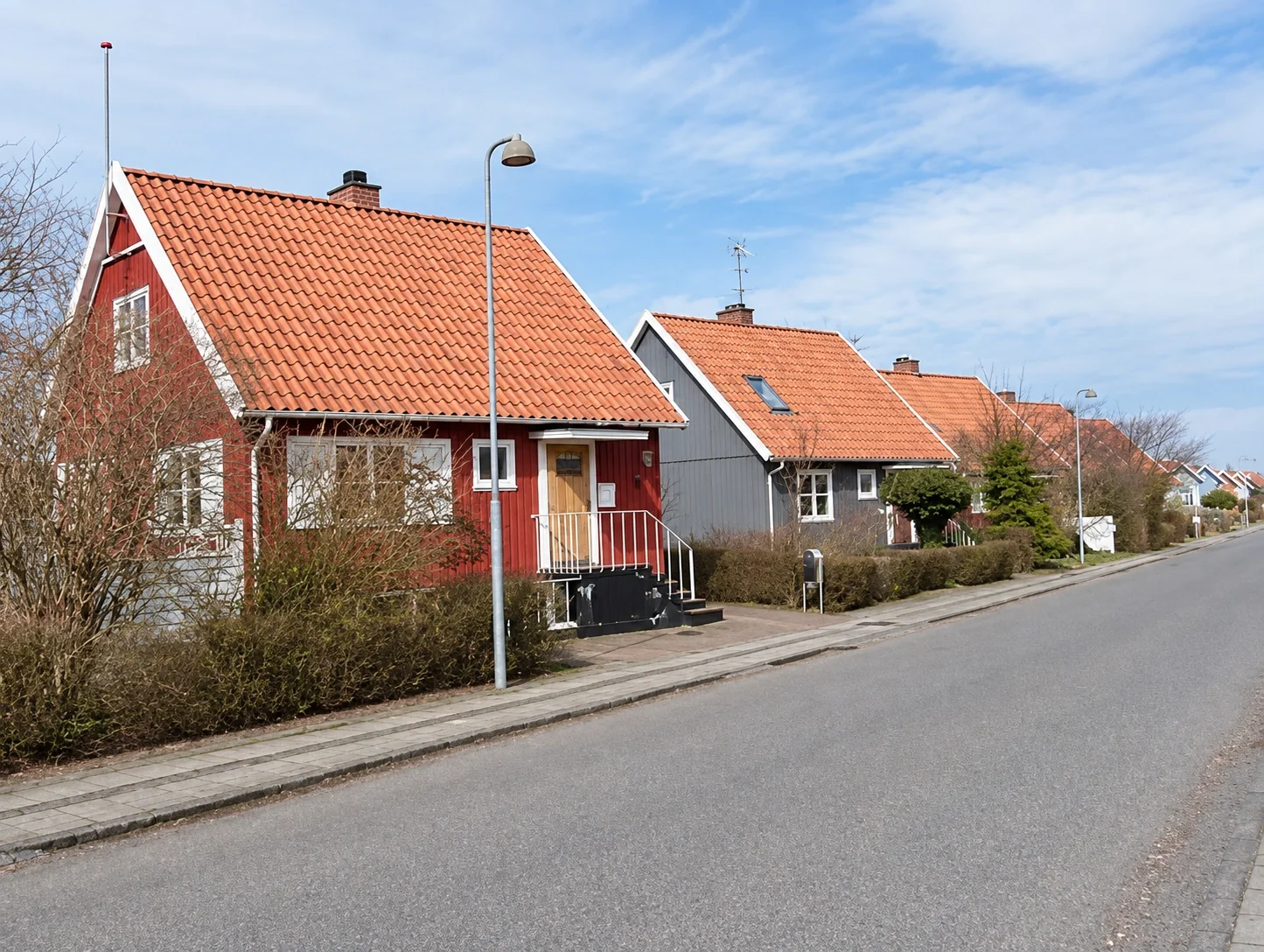 Række af røde og grå svenskerhuse langs brostensgade
