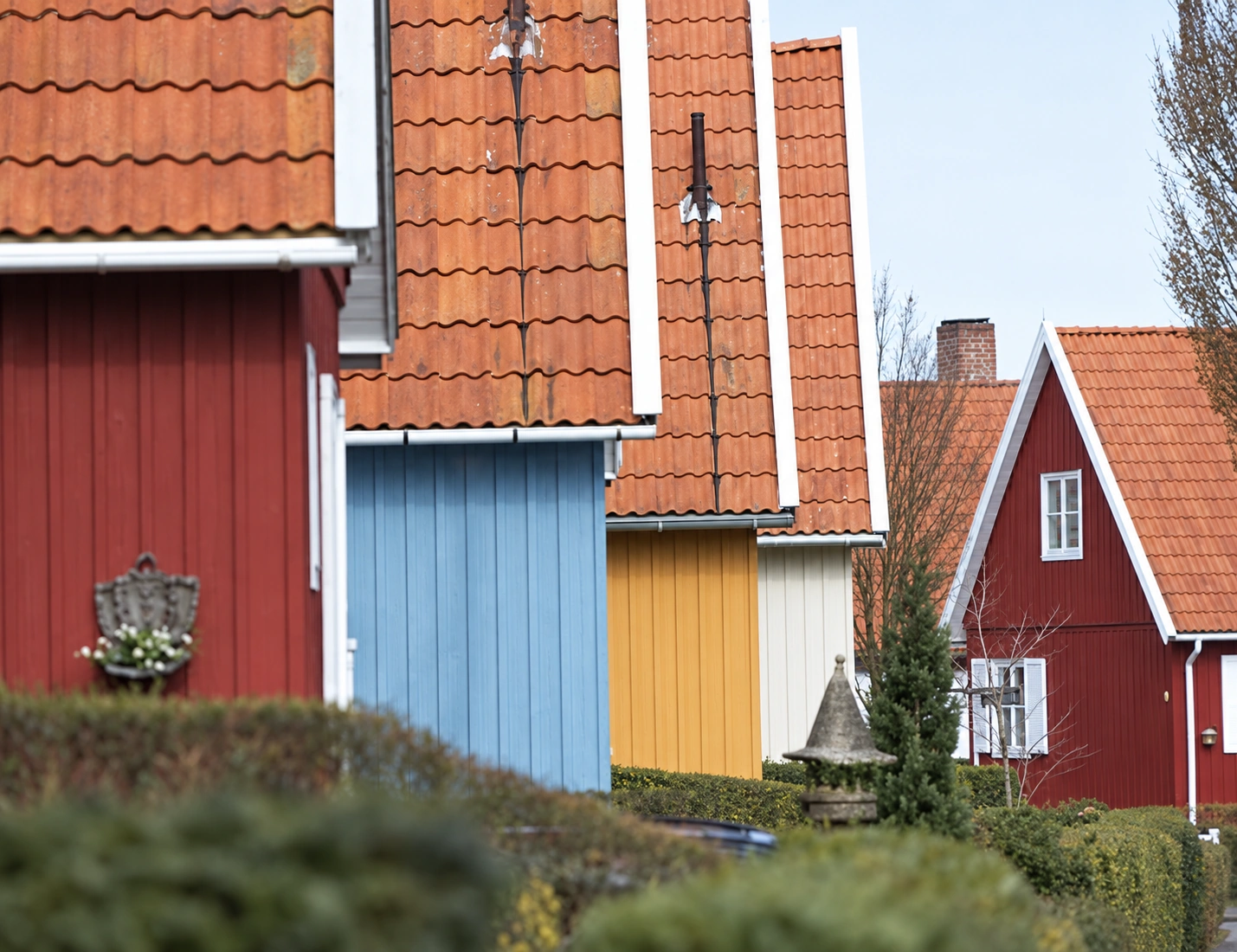 Gavle og tegltage på svenskerhuse i rød, blå og gul med hvide vindskeder