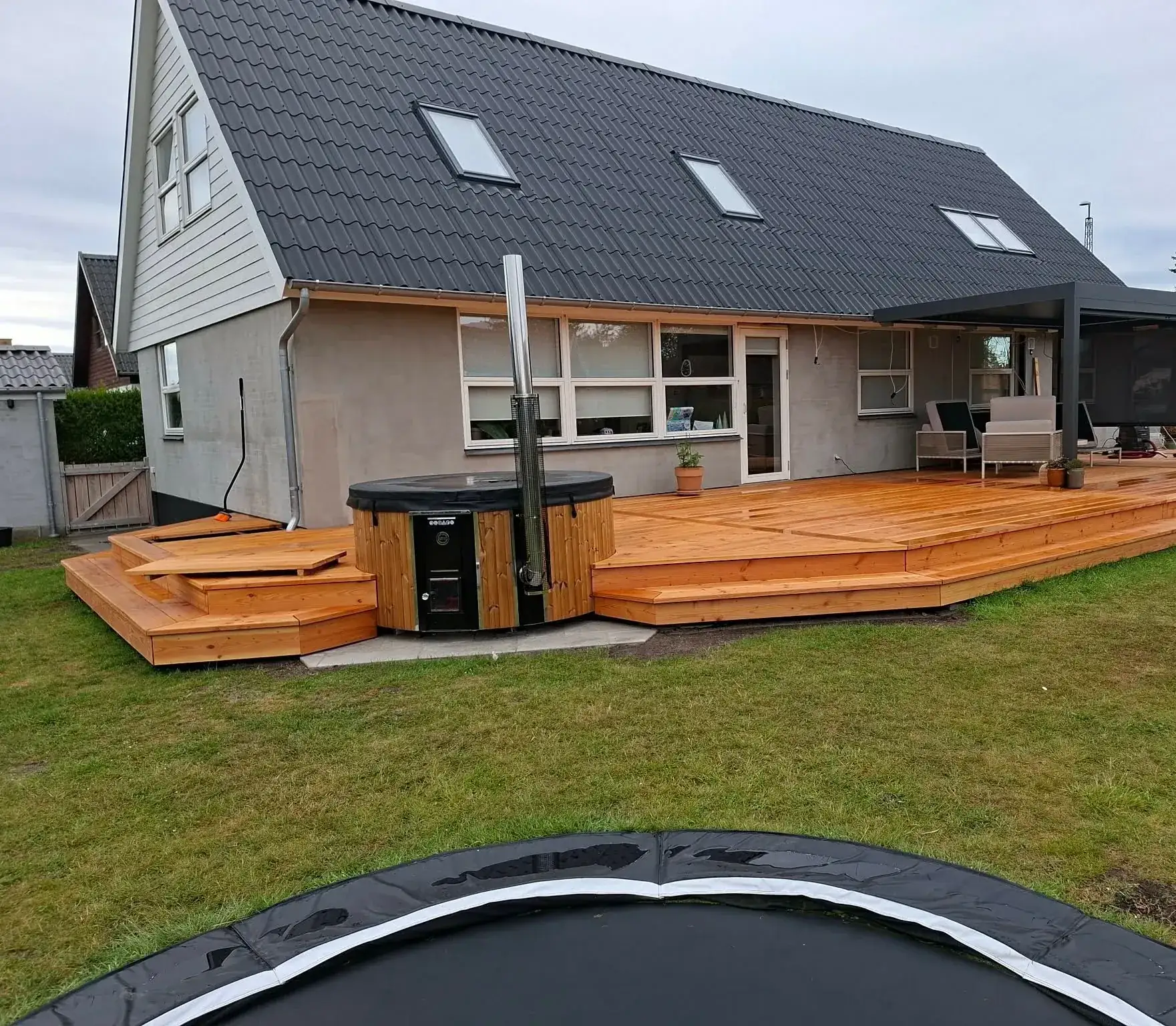 Stor lærketerrasse med brede trin og hot tub ved hvidt hus
